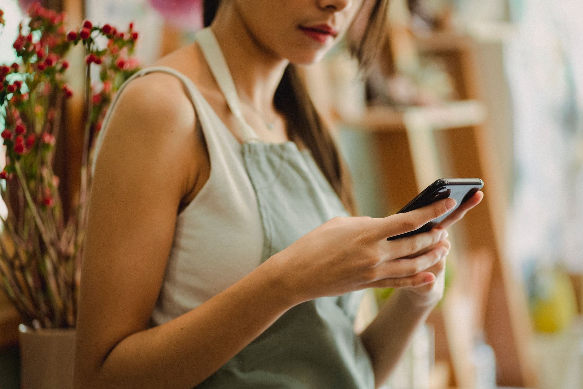 Shop owner answering customer messages on her phone between orders