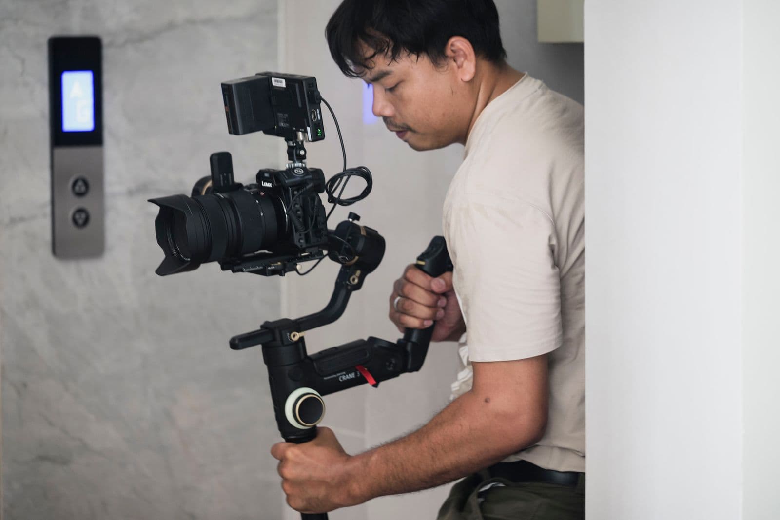 Videographer operating a camera on a handheld stabilizer indoors